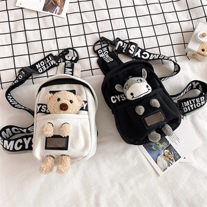 Detail of canvas chest bags with cute plush dolls and printed wide shoulder straps