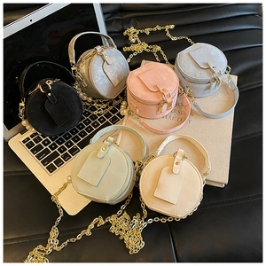 Détail de mini sacs ronds en velours avec anses en perles et chaînes dorées colorées