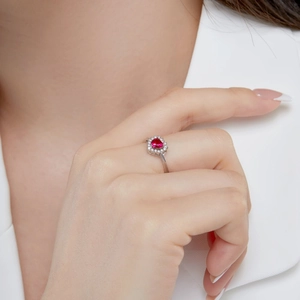 Close-up of heart-shaped ruby ring in S925 silver with sparkling zircon halo on finger