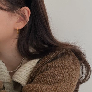 Close-up of a model wearing golden ball earrings and a delicate white pearl necklace