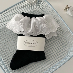Women's black cotton crew socks with white lace ruffle cuffs and bow cutout pattern