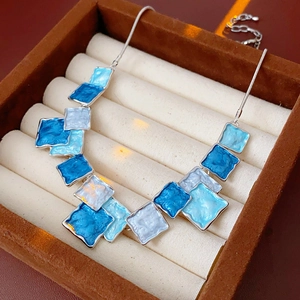 Detail of blue and white enamel square pendants on a silver-tone snake chain necklace