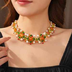 Gros plan détaillé du collier vintage doré avec gemmes orange, perles et strass colorés