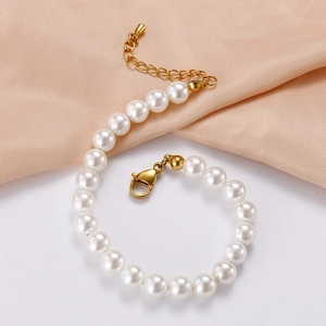 Détail du bracelet en perles avec fermoir mousqueton doré sur satin couleur champagne