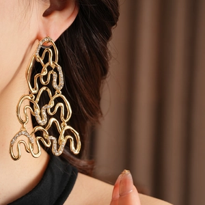Close-up of luxury gold irregular geometric earrings with micro-set diamonds on model