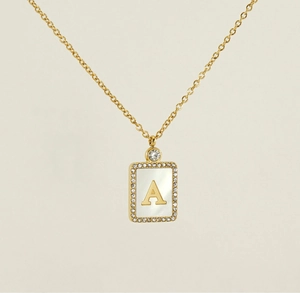 Detail of square gold necklace featuring shell letter A pendant with sparkling crystals