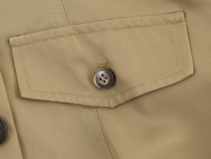 Detail der khakifarbene Jacke mit Taschenklappe, braunem Knopf und Twill-Stoffstruktur