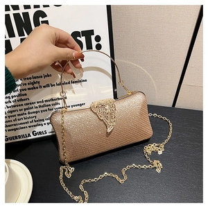 Close-up of champagne gold evening clutch with sequined texture and leaf clasp detail