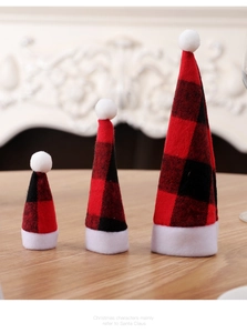 Three-piece red plaid Christmas hat decor displayed on a rustic wooden table surface