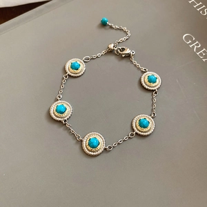 Macro shot of turquoise stones in gold and silver settings on a refined chain bracelet