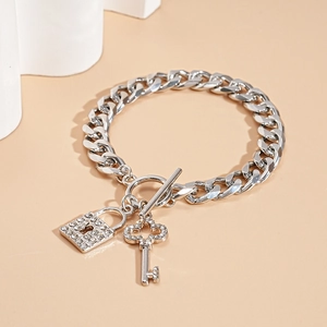 Detail of silver Cuban chain bracelet featuring rhinestone lock and key charms with OT clasp