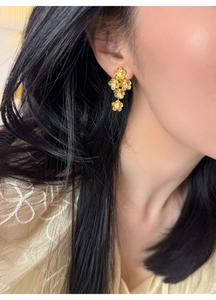 Close-up of golden vintage floral earrings with zircons worn by a model