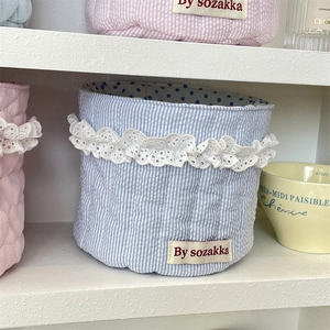 Detail of blue striped cotton storage basket with white lace trim and quilted texture