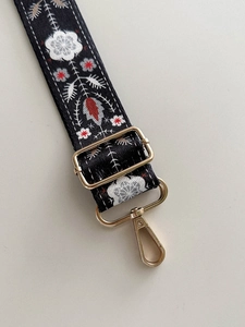 Detail of 38mm wide canvas strap with red and white floral embroidery and gold metal clips