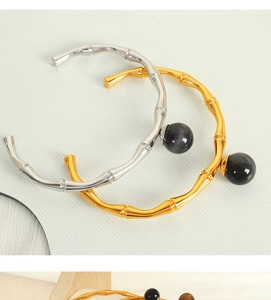Detailed macro view of gold and silver bamboo style open bracelets with black bead accents