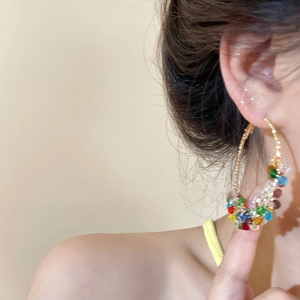 Gros plan de créoles dorées avec des perles de cristal colorées portées par un mannequin