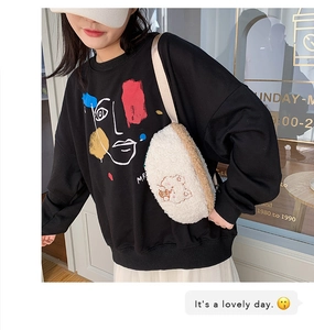 Close-up of white plush crossbody bag with bear embroidery and casual black sweatshirt