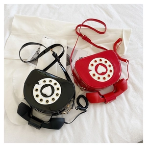 Close-up of creative telephone-shaped patent leather crossbody bag with heart dial details