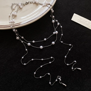 Detailaufnahme einer mehrlagigen Silberkette mit eleganten weißen und grauen Perlen