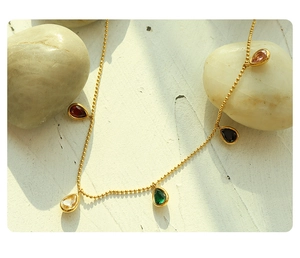 Detail of gold beaded chain necklace with five colorful teardrop zircon pendants