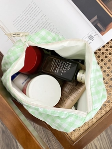 Vue détaillée d'une trousse de maquillage en coton matelassé à carreaux verts avec produits