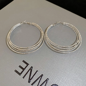 Detail of silver multi-layered hoop earrings with frosted textured surface and glitter finish
