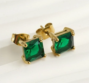Macro shot of 18k gold earrings with square-cut green zircons and butterfly backs