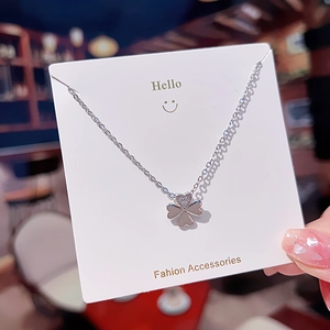 Silver four-leaf clover pendant necklace with minimalist crystal center on display card