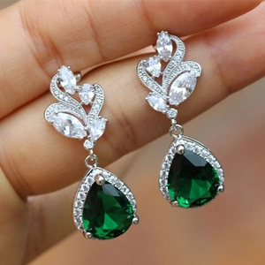 Close-up of vintage emerald green pear-cut earrings with brilliant white zircon halos