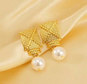Detail showing gold woven texture metal studs with hanging white pearls on satin