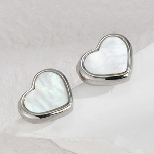 Minimalist silver heart earrings with white mother-of-pearl inlay on a stone background