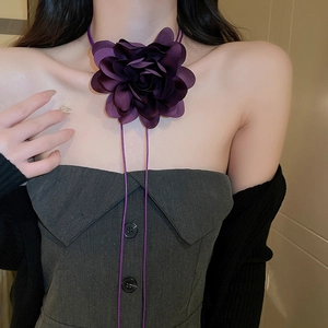 Close-up of a large purple fabric flower choker with long ribbons on a model neck