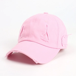 Detail of pink washed cotton baseball cap featuring vintage distressed ripped edge texture