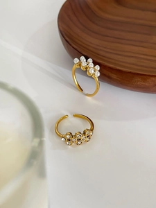 Detailed view of two 18k gold plated adjustable rings with pearls and zircon stones