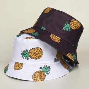 Detail of cartoon pineapple bucket hats in white and purple with all-over print design