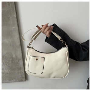 Detail of cream white faux leather bag featuring a square flap pocket and gold snap button