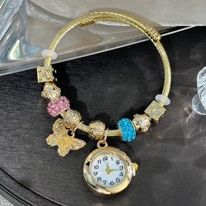 Detailed shot of golden charm bracelet watch with rhinestone butterfly and floral beads