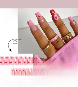 Detail of pink French tip press-on nails with red heart patterns and wavy designs