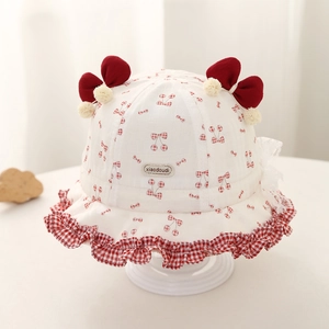 Détails d'un chapeau bébé à imprimé cerise avec nœuds et bordure volantée à carreaux
