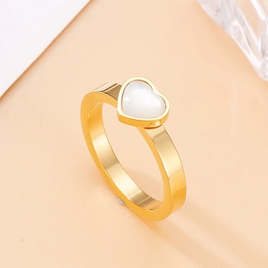 Macro detail of gold-plated heart ring with white opal inlay and polished band texture