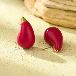 Rose red teardrop earrings in titanium steel with gold metal accents on sandy stone