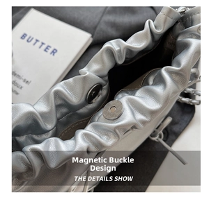 Detail of silver metallic tote bag with magnetic closure and polished metal chain strap