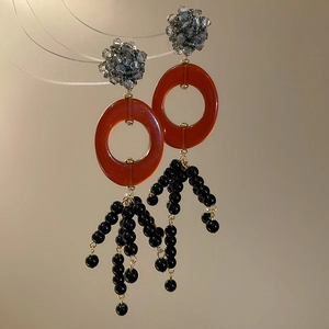 Detailed macro view of retro orange resin ring earrings with black beaded tassels