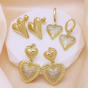 Elegant gold heart earrings set with sparkling zircons on a luxury silk background