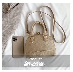 Detail of beige faux crocodile shell bag with golden zipper next to a smartphone