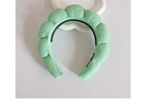 Close-up of light green sponge headband with textured fabric and non-slip inner teeth