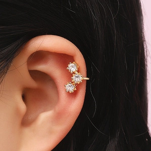 Detailed view of elegant gold ear cuff with three sparkling zircons on model ear