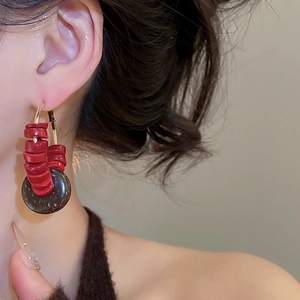 Détail des perles rouges rétro et des pompons en coque de coco sur boucles d'oreilles