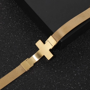 Close-up of golden cross charm on a Milanese mesh adjustable stainless steel bracelet