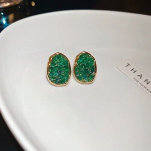 Macro shot of vintage style green sphere stud earrings with gold plating and crystal texture